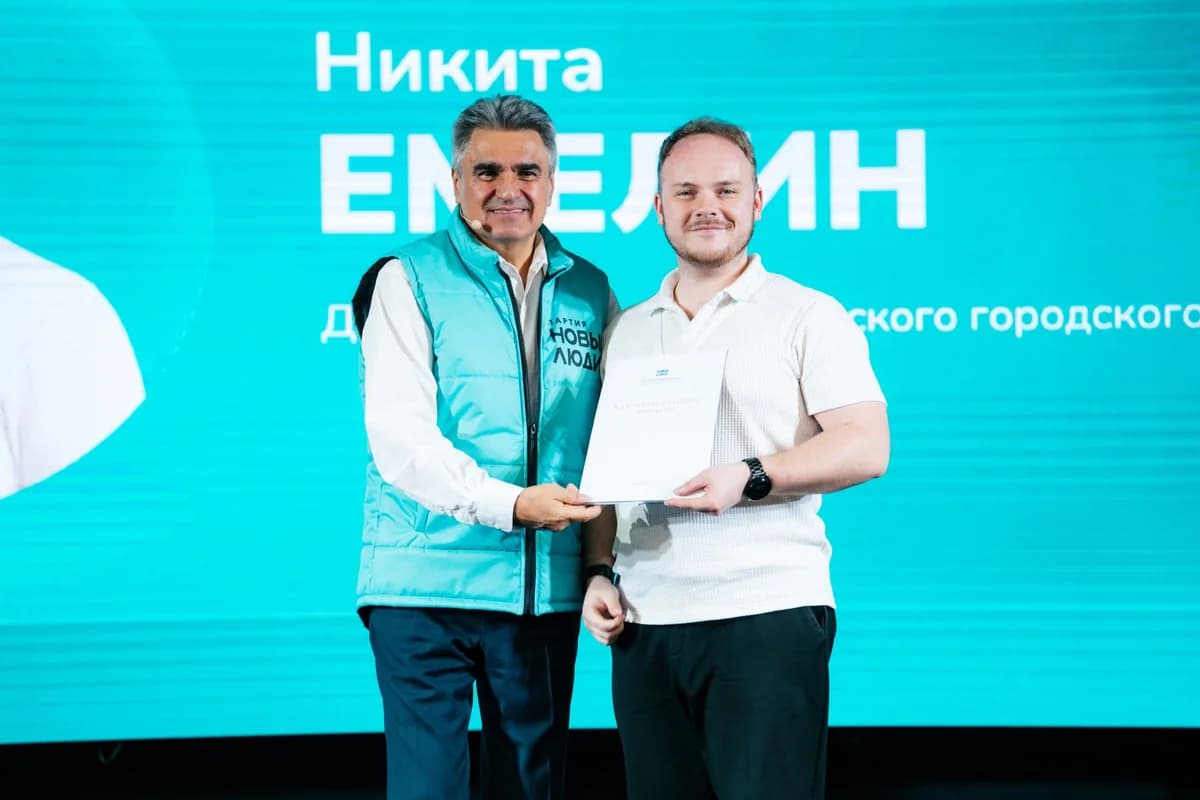 Никита Емелин получает документ на сцене общественного мероприятия